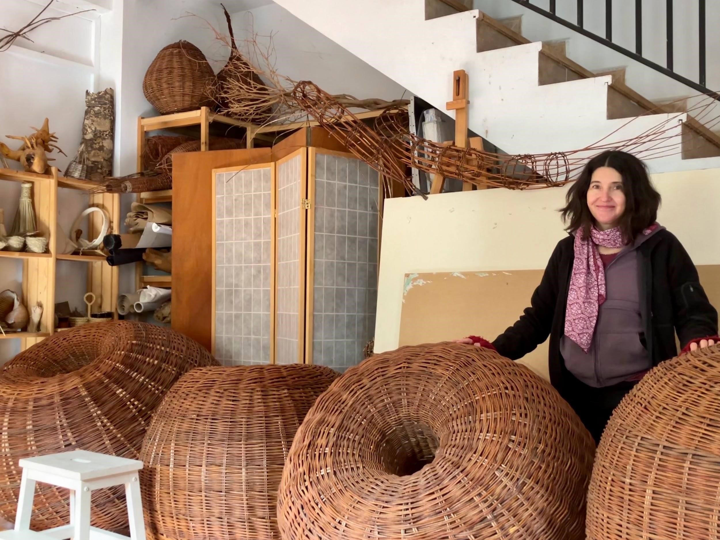 La artista Lucía Loren en su taller de Horcajuelo de la Sierra (Madrid) con algunas de sus obras, como los toroides de mimbre que deposita en el campo para que se unan a la naturaleza. / Jon Gurutz Arranz Izquierdo